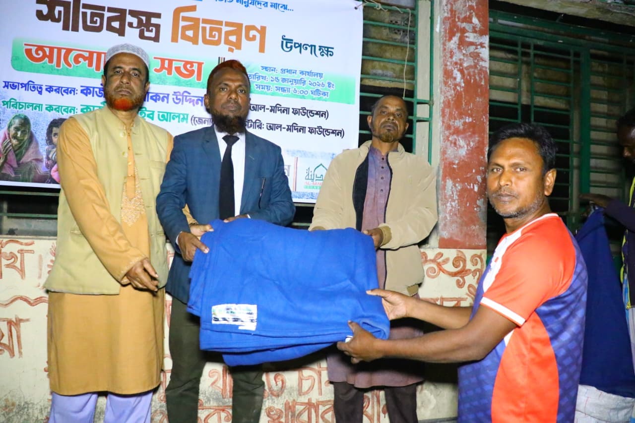 কমলা ও নীল পোশাক পরা একজন পুরুষ নীল কম্বল গ্রহণ করছেন।