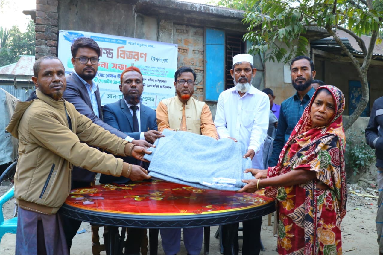 ছাপার শাড়ি পরা একজন নারী কয়েকজনের কাছ থেকে ধূসর কম্বল নিচ্ছেন।